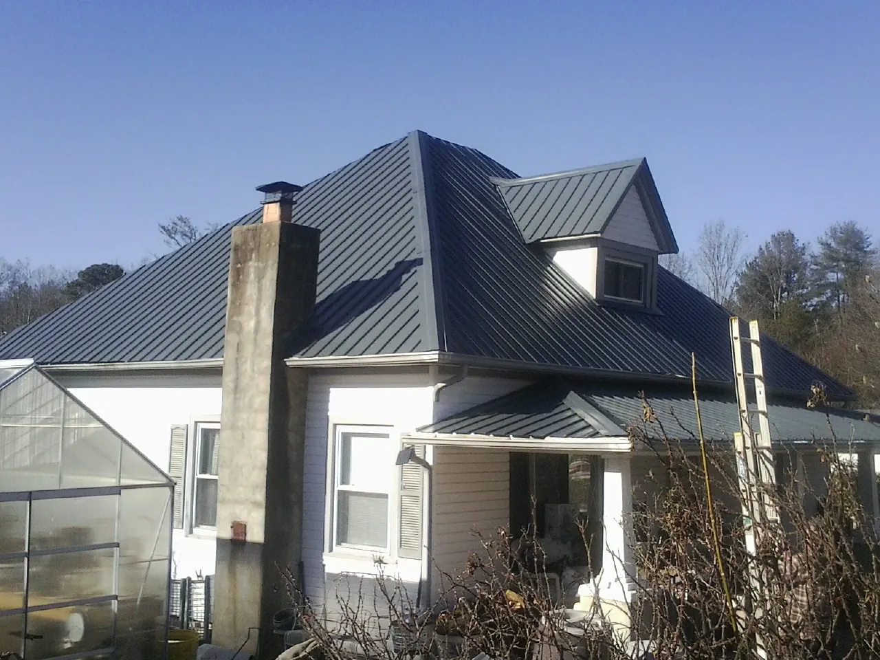 Dark blue standing seam metal roof on a white farmhouse with dormer — Slate & Tile Roof Repair by Roofing Brothers in Leavittsburg