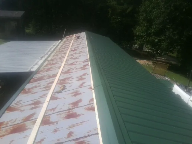 Old rusted panels beside newly installed green metal roofing — Wind Damage Roof Repair by Roofing Brothers in Leavittsburg
