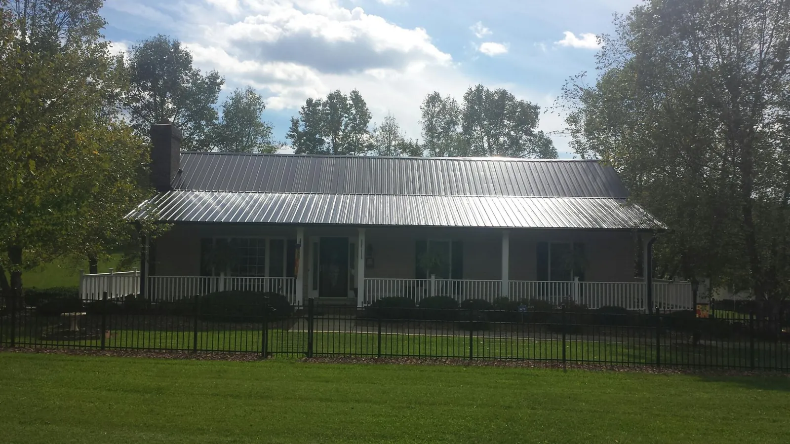 Gray metal roof on a brick ranch with a full width front porch — Gutter Guard Installation work by our crew in Leavittsburg