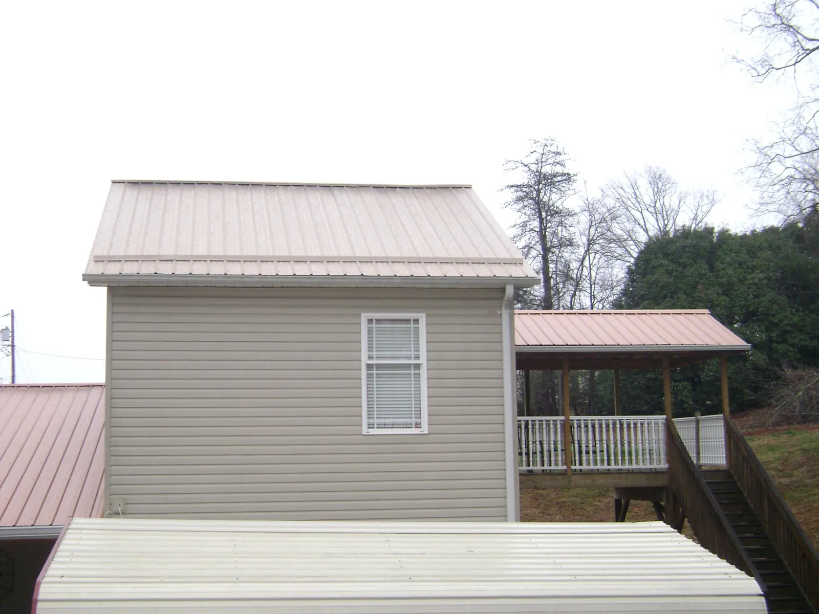 Tan metal roofs on a two story addition and attached porch, from a Roof Replacement job in Leavittsburg
